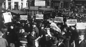 حشد من الرجال يرفعون صحفًا بعنوان "ألمانيا تستسلم"